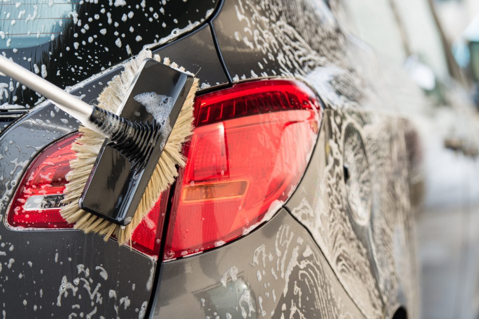 Person washing a car with scrub brush.