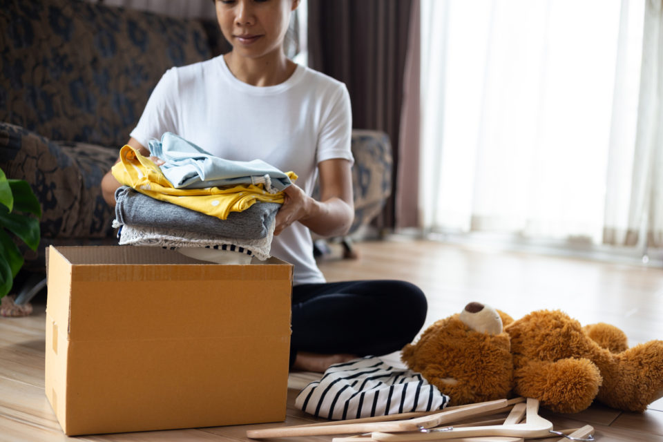 Woman holding Clothes with Donate Box In her room