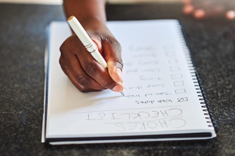 Cropped shot of a woman checking off tasks on a chore list at home