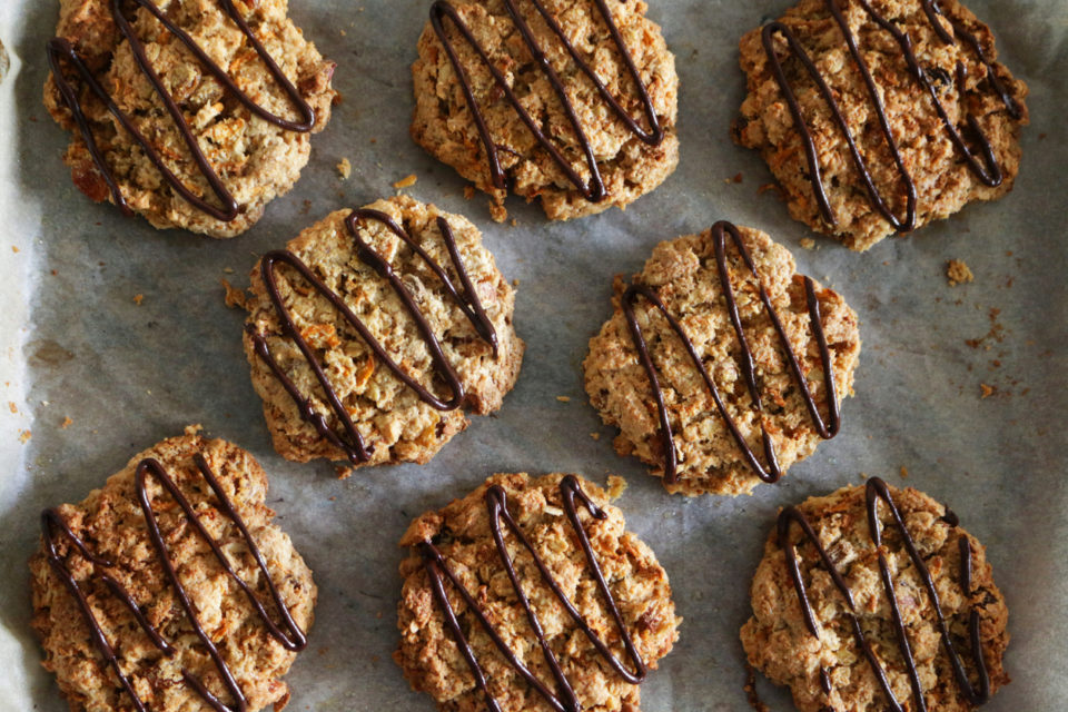 Carrot cookies with chocolate drizzle on parchment paper
