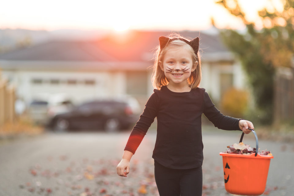 Young girl in black cat costume goes trick or treating