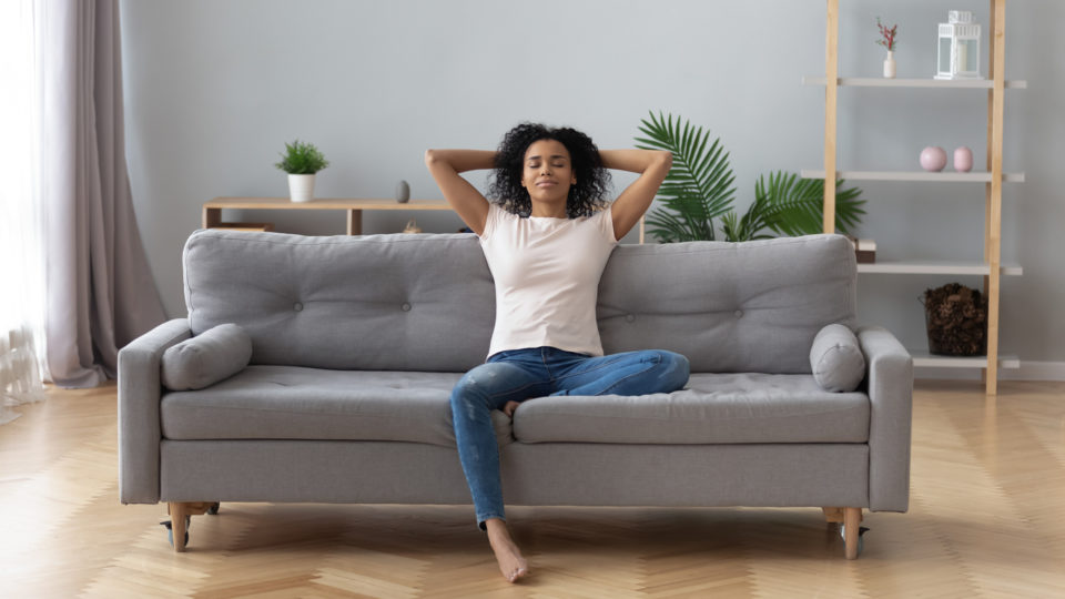 A woman enjoys the cool breeze in her home.