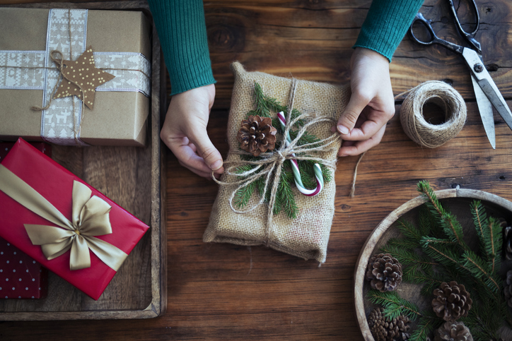 Unrecognizable woman wrapping Christmas presents in a crafty way.