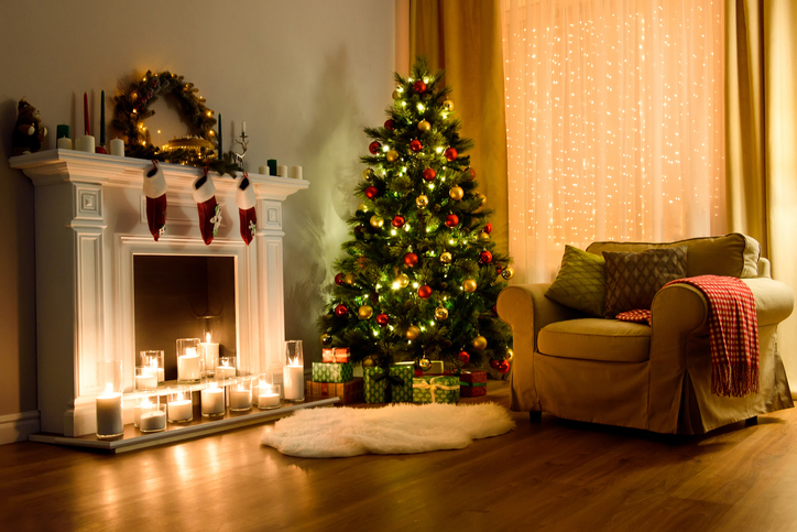 A cozy living room lighted with numerous lights decorated ready to celebrate Christmas. Christmas room interior design, Xmas tree decorated by lights, candles and garland lighting indoors fireplace.